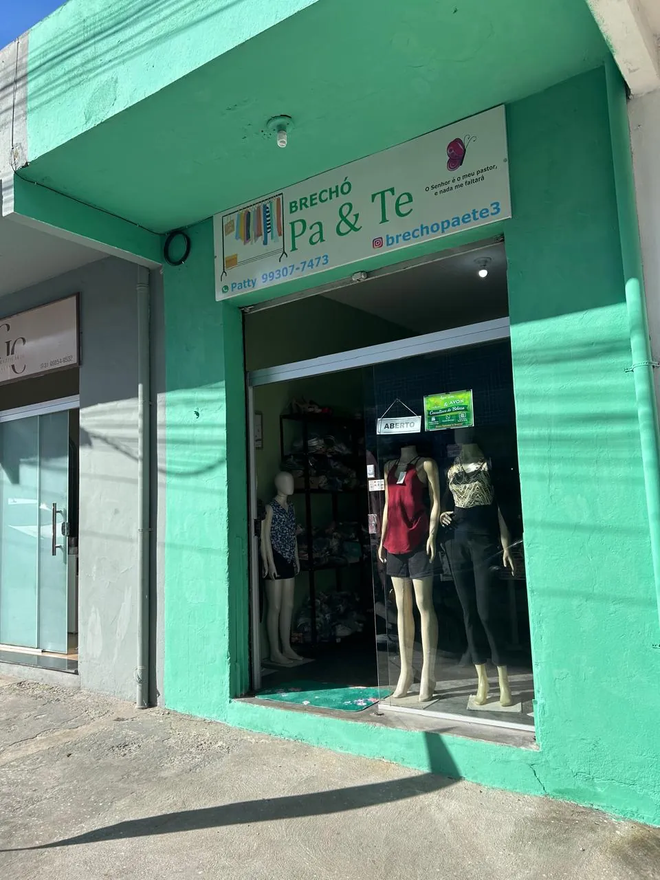 Fachada verde do Brechó Pa & Te com placa, porta de vidro e manequins na vitrine